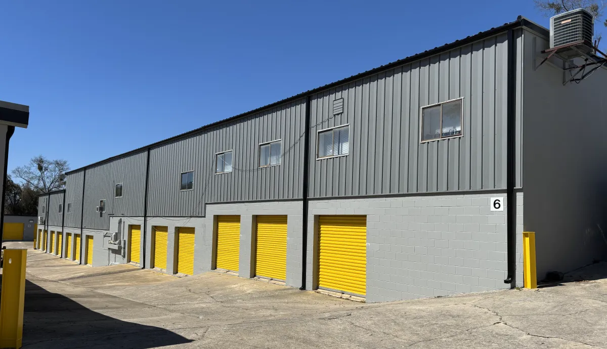 Two-story gray self-storage building with bright yellow roll-up doors.